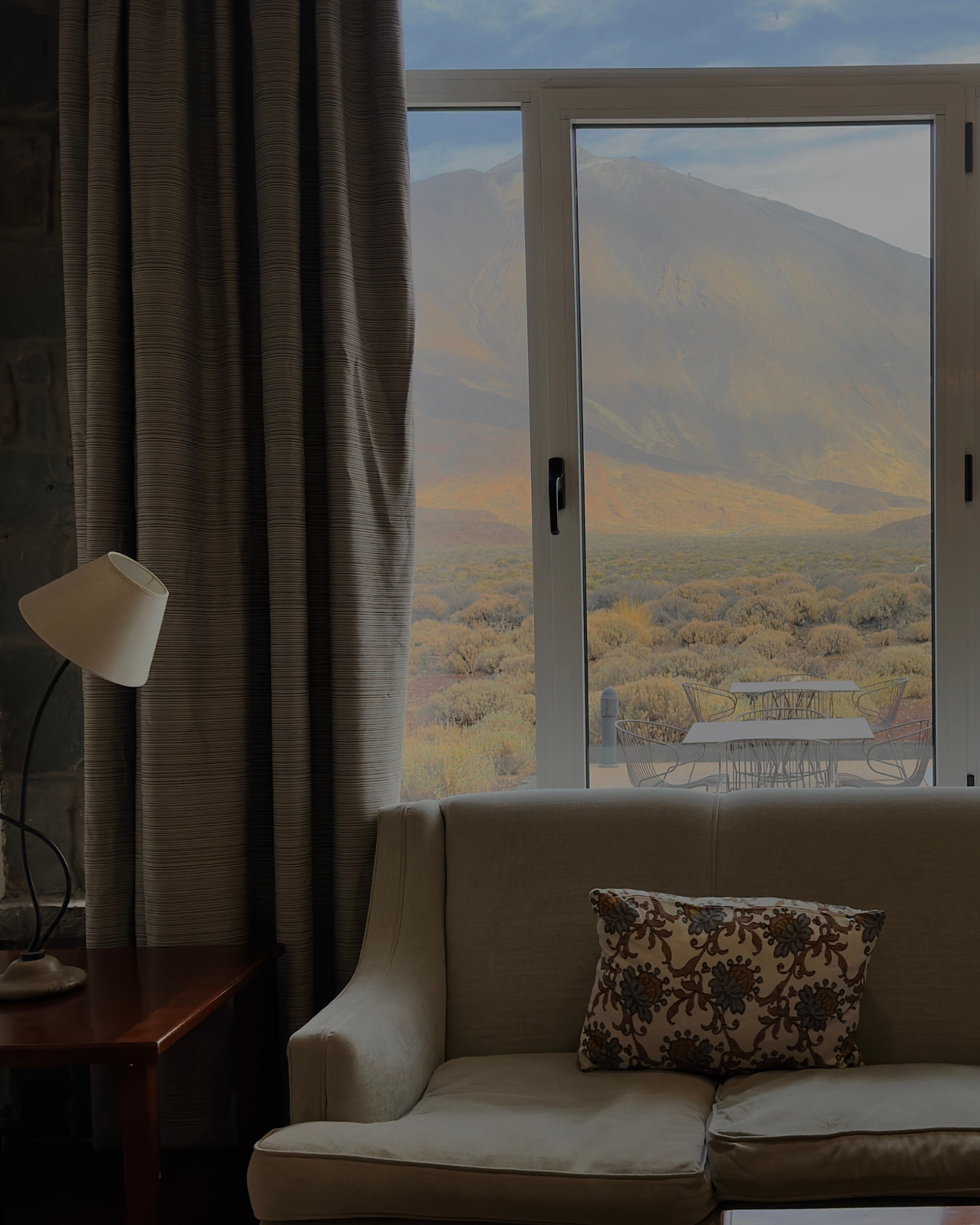 A quiet sitting room with a wide window looking out over mountains